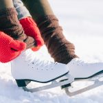 Girl in dress skates mittens tying shoelaces