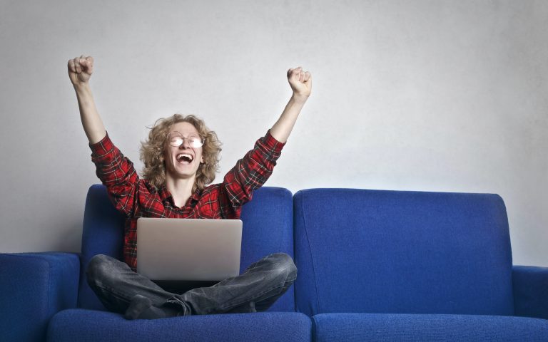 Woman sitting on couch cheering with excitement.